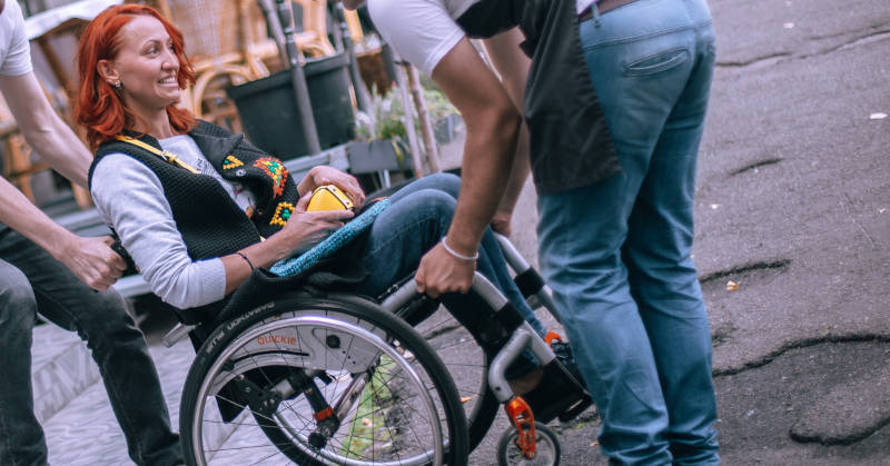 Mujer en silla de ruedas ayudada a acceder a un local